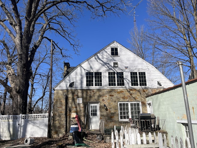345 S Cochran Ave, Charlotte, MI 48813 - back of property featuring fence, a chimney, a gate, and stone siding