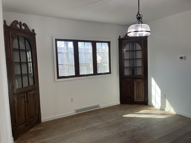 345 S Cochran Ave, Charlotte, MI 48813 - unfurnished dining area featuring baseboards, wood finished floors, and visible vents