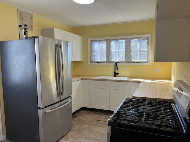 345 S Cochran Ave, Charlotte, MI 48813 - kitchen with light countertops, white cabinetry, a sink, dark wood finished floors, and stainless steel appliances