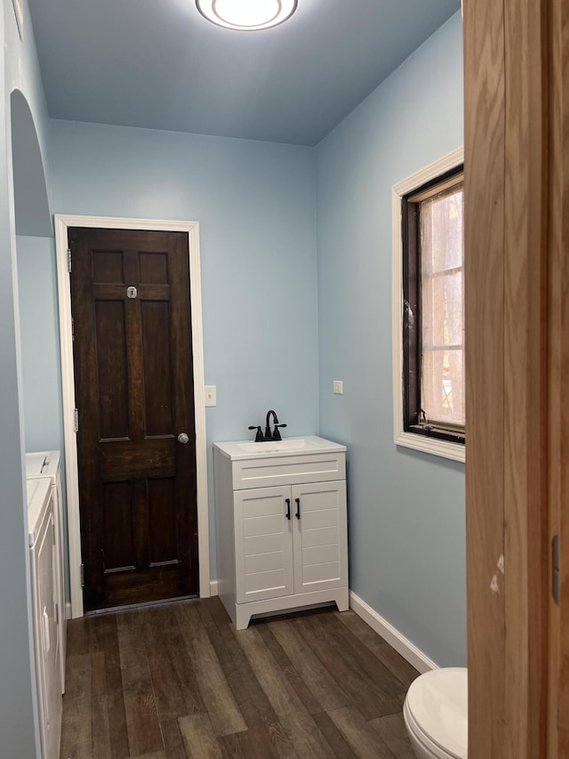 345 S Cochran Ave, Charlotte, MI 48813 - bathroom featuring vanity, toilet, baseboards, wood finished floors, and washing machine and dryer