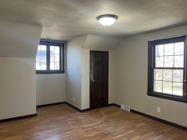 345 S Cochran Ave, Charlotte, MI 48813 - additional living space with baseboards, visible vents, lofted ceiling, and dark wood-type flooring