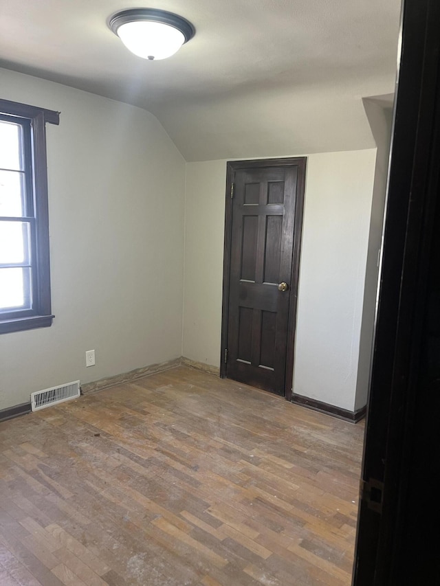 345 S Cochran Ave, Charlotte, MI 48813 - empty room featuring baseboards, visible vents, wood finished floors, and vaulted ceiling