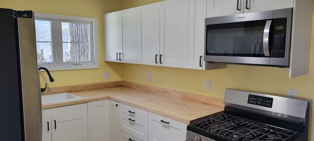 345 S Cochran Ave, Charlotte, MI 48813 - kitchen featuring white cabinetry, appliances with stainless steel finishes, butcher block counters, and a sink
