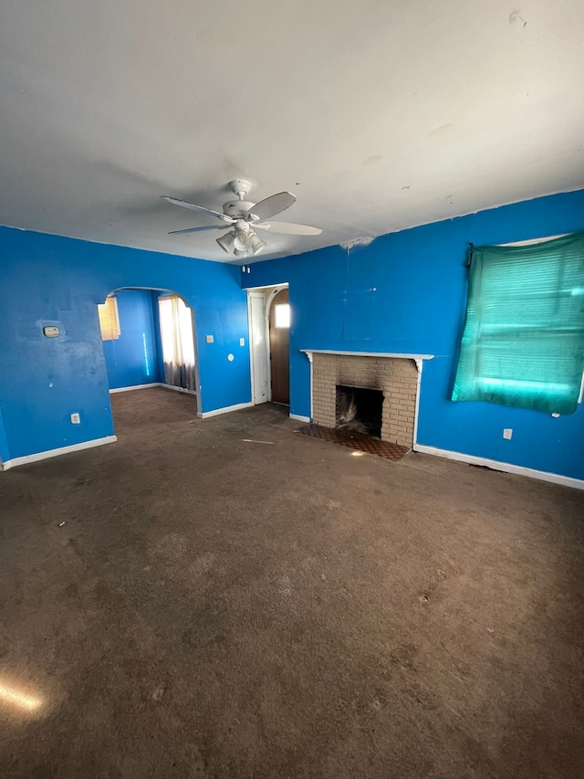 14811 Robson St, Detroit, MI 48227 - unfurnished living room with carpet, baseboards, arched walkways, a ceiling fan, and a fireplace
