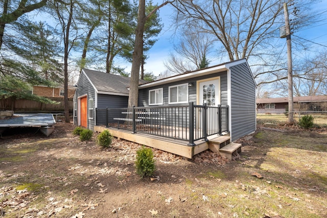 view of front of house with a wooden deck, an outbuilding, fence, and a garage