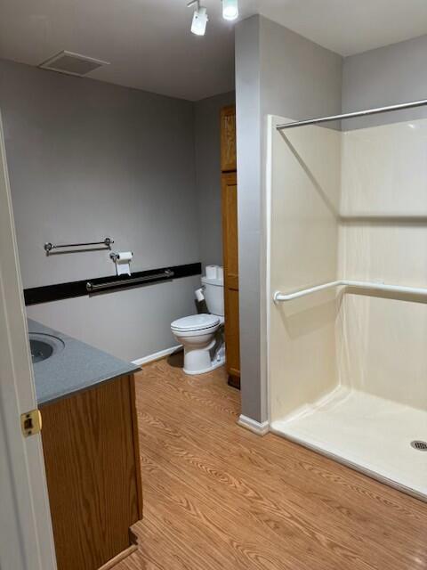 full bath with toilet, vanity, a shower stall, wood finished floors, and visible vents