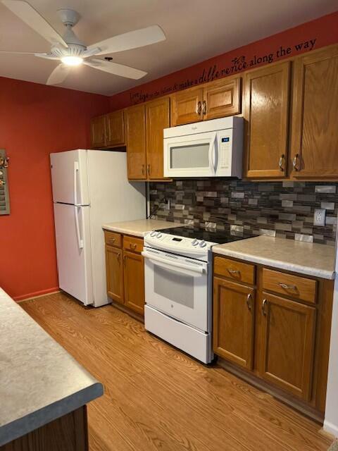 kitchen with white appliances, brown cabinets, a ceiling fan, tasteful backsplash, and light wood-type flooring