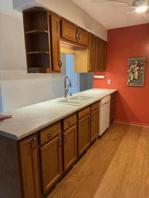 kitchen featuring light countertops, a sink, a ceiling fan, white dishwasher, and light wood-style flooring