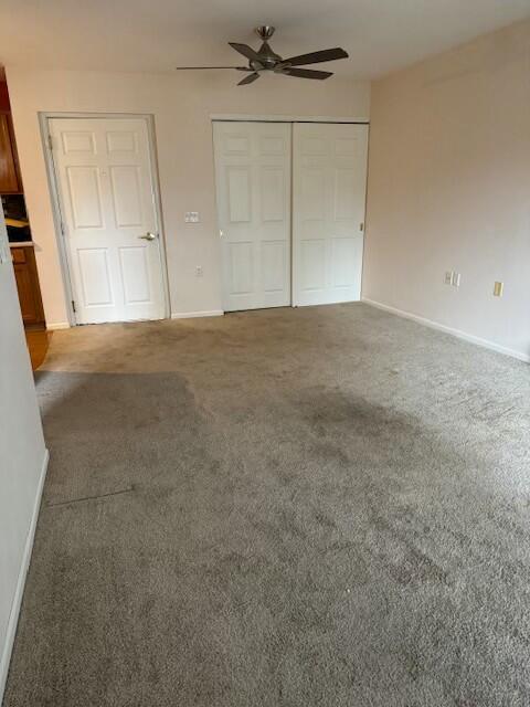 unfurnished bedroom featuring carpet flooring, baseboards, a closet, and ceiling fan