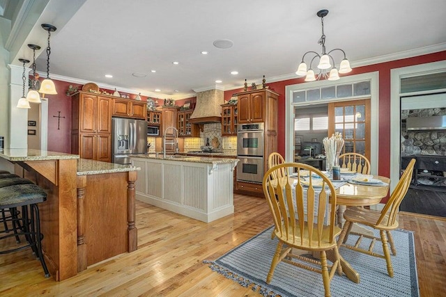 dining space featuring ornamental molding, recessed lighting, a notable chandelier, and light wood-type flooring
