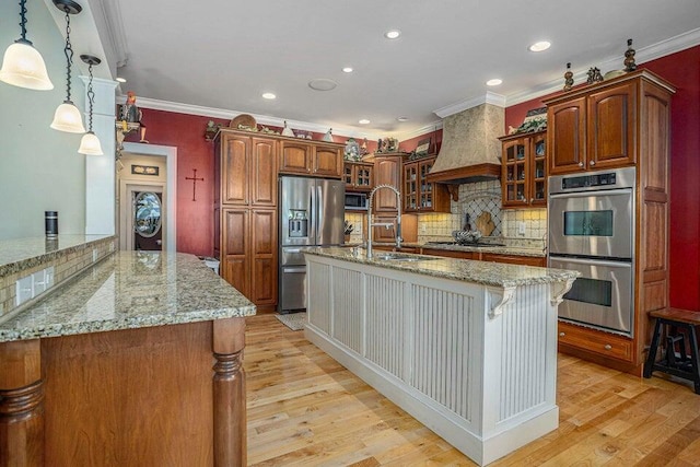 kitchen with custom range hood, light stone countertops, a sink, and stainless steel appliances