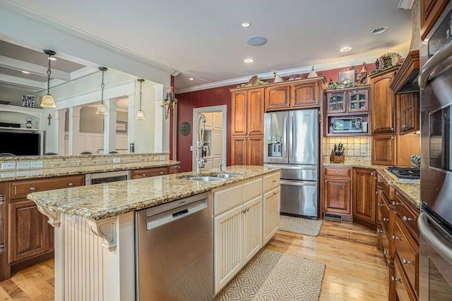 kitchen with a kitchen island with sink, light wood-style flooring, a sink, and stainless steel appliances