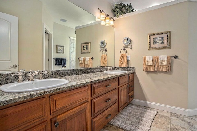 full bathroom with baseboards, double vanity, and a sink