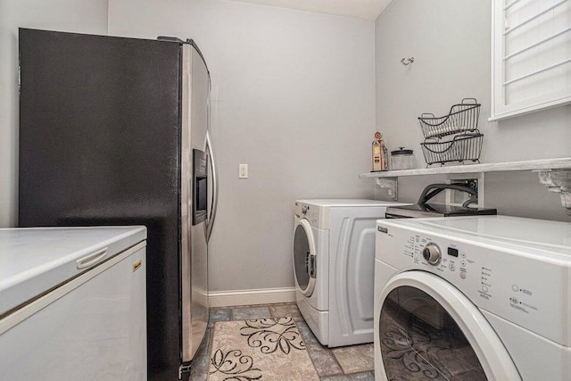 laundry area with washing machine and clothes dryer, stone finish flooring, baseboards, and laundry area