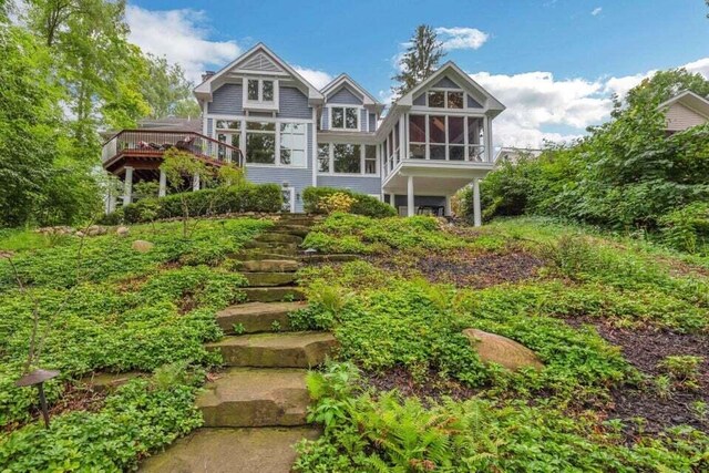 back of house featuring a sunroom, a wooden deck, and stairs