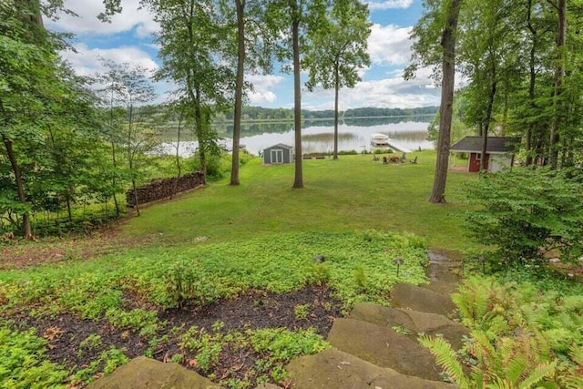 view of yard featuring an outbuilding, a water view, and a storage shed