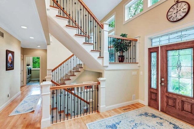 entrance foyer featuring baseboards, a high ceiling, wood finished floors, and plenty of natural light