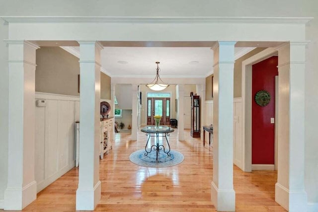 hall featuring crown molding, light wood finished floors, and ornate columns