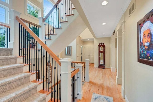 stairway featuring baseboards, visible vents, wood finished floors, and a healthy amount of sunlight
