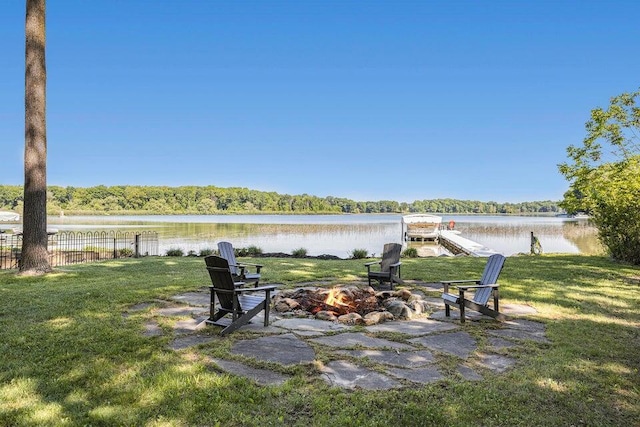 view of yard featuring a view of trees, a fire pit, a water view, and fence