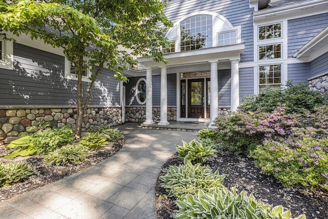 view of exterior entry with stone siding and a porch