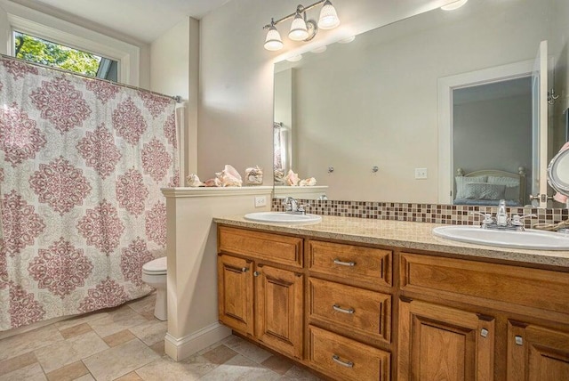 full bath featuring connected bathroom, toilet, decorative backsplash, and a sink