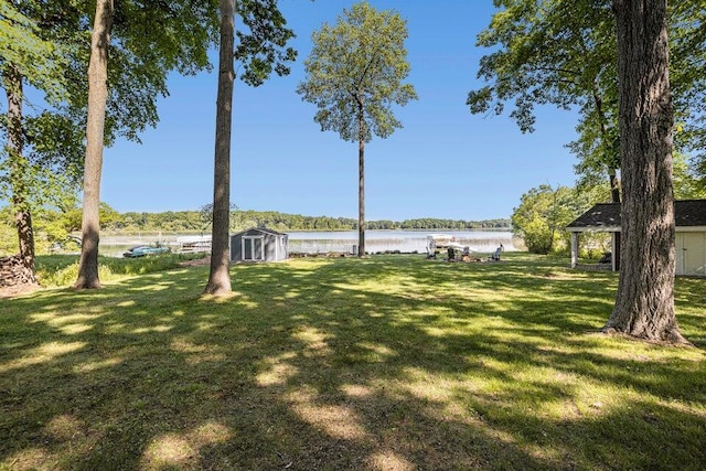 view of yard featuring an outbuilding, a storage shed, and a water view