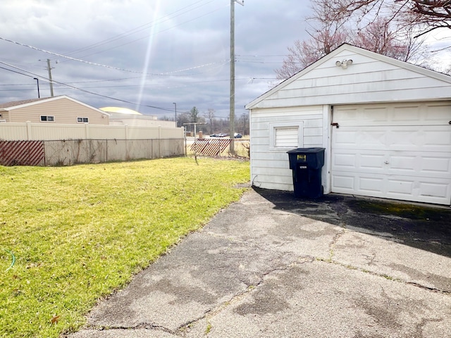 view of yard featuring driveway, a garage, fence, and an outdoor structure