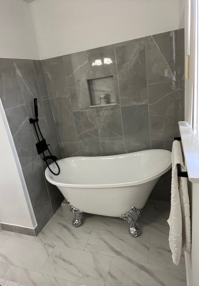 full bathroom with marble finish floor, a soaking tub, and tile walls