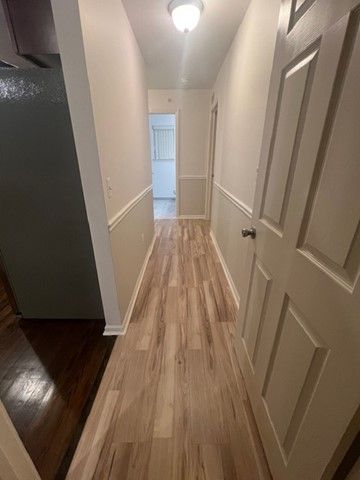 hallway featuring light wood-style floors and a decorative wall