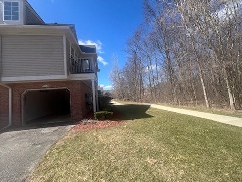 view of side of property featuring driveway, an attached garage, and a lawn