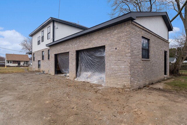 23708 Lexington Ave, Eastpointe, MI 48021 - view of side of home featuring stucco siding, brick siding, a garage, and dirt driveway