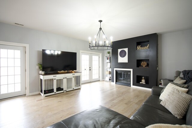 living area featuring visible vents, wood finished floors, a notable chandelier, and plenty of natural light