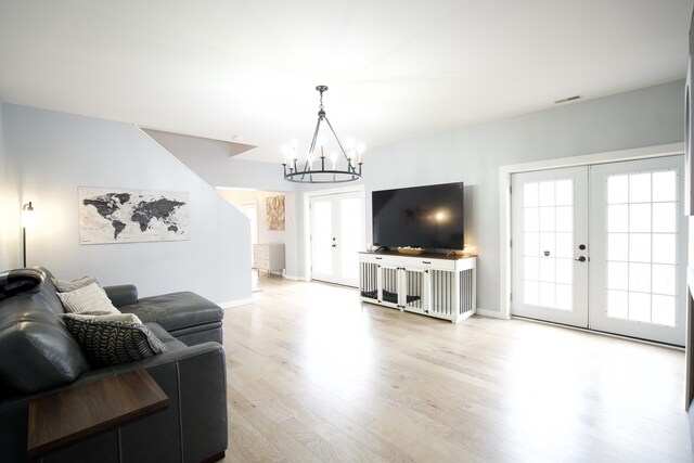 living room with a notable chandelier, french doors, light wood-type flooring, baseboards, and visible vents