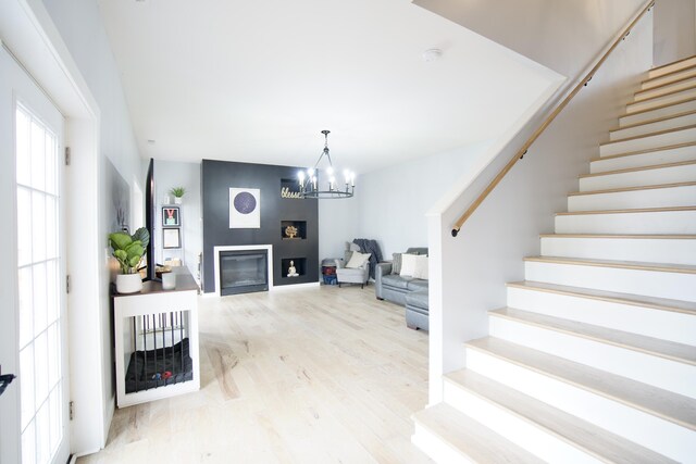 living area featuring a notable chandelier, wood finished floors, stairway, and a fireplace