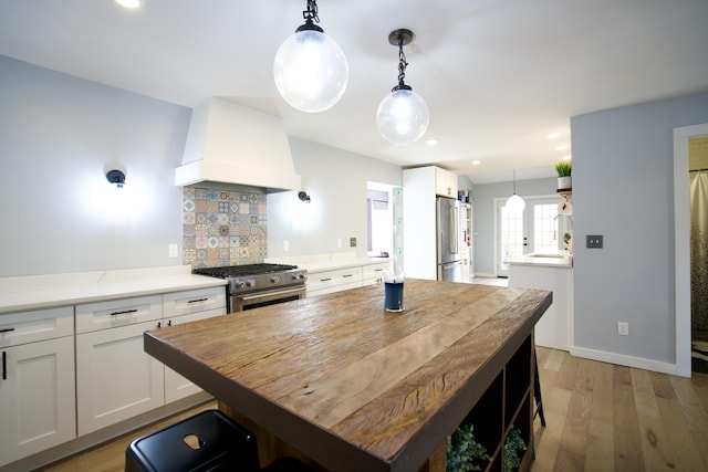 kitchen with premium range hood, tasteful backsplash, white cabinetry, light wood-type flooring, and high quality appliances