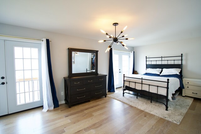 bedroom featuring french doors, a notable chandelier, and light wood finished floors