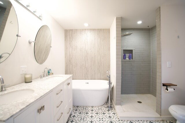 bathroom with a stall shower, double vanity, a freestanding tub, and a sink