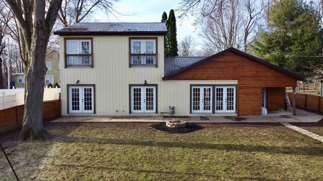 rear view of property featuring metal roof, fence, french doors, and a patio