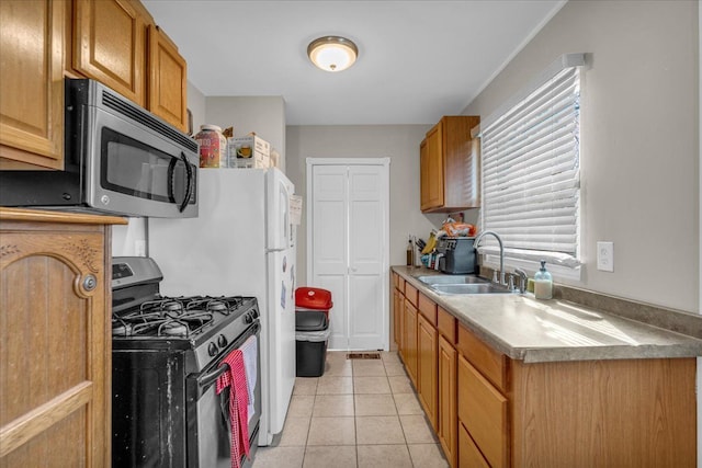 kitchen featuring a sink, appliances with stainless steel finishes, light tile patterned floors, and brown cabinets