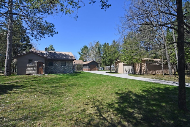 4331 N Burr Oak Rd, Lincoln, MI 48742 - view of green lawn with concrete driveway, a garage, and an outbuilding