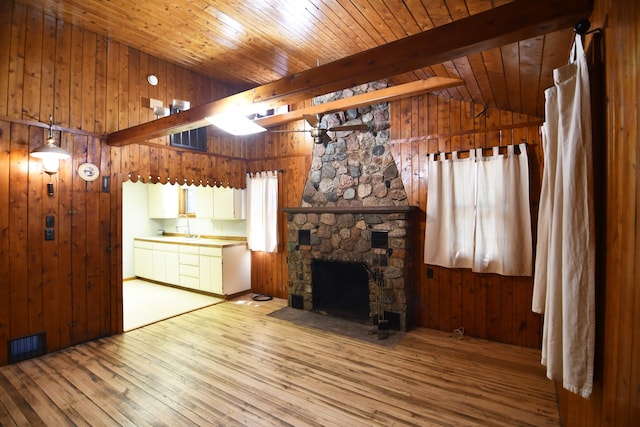 4331 N Burr Oak Rd, Lincoln, MI 48742 - unfurnished living room featuring light wood finished floors, wood walls, wood ceiling, a stone fireplace, and a sink