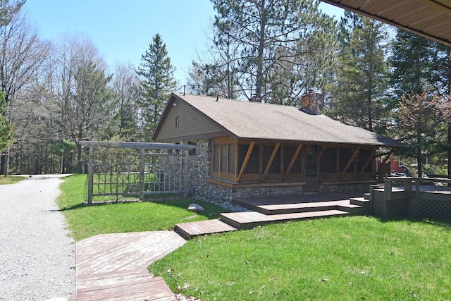 4331 N Burr Oak Rd, Lincoln, MI 48742 - view of front of property featuring a chimney, a front yard, roof with shingles, a deck, and stone siding