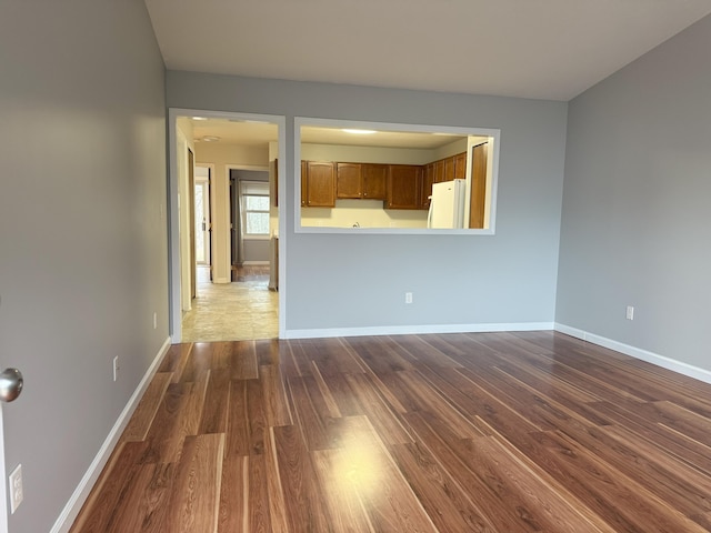 unfurnished living room featuring baseboards and dark wood-style flooring
