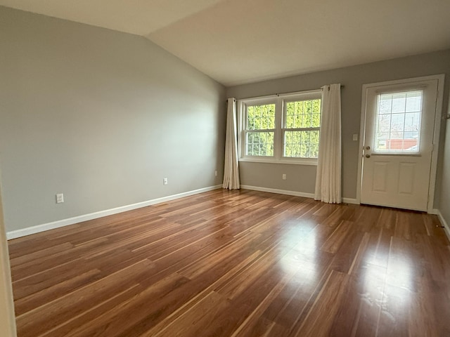 interior space featuring baseboards, vaulted ceiling, and wood finished floors