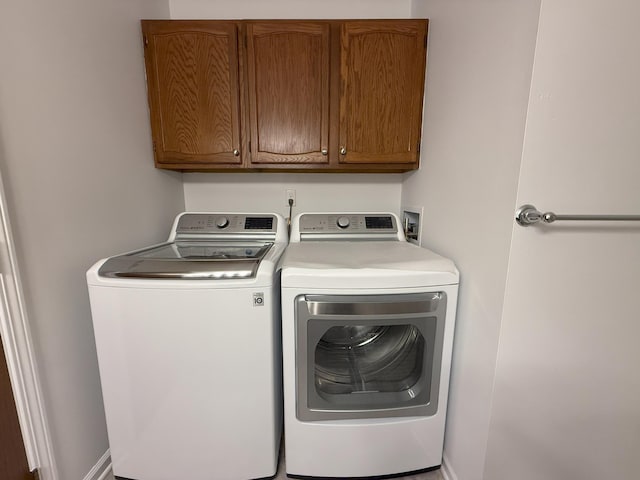 washroom featuring cabinet space and washer and clothes dryer