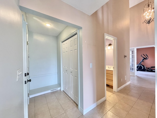 foyer featuring light tile patterned floors, baseboards, and a chandelier