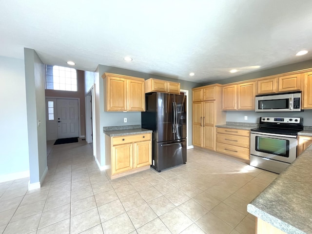 kitchen with appliances with stainless steel finishes, light brown cabinetry, light tile patterned floors, recessed lighting, and baseboards