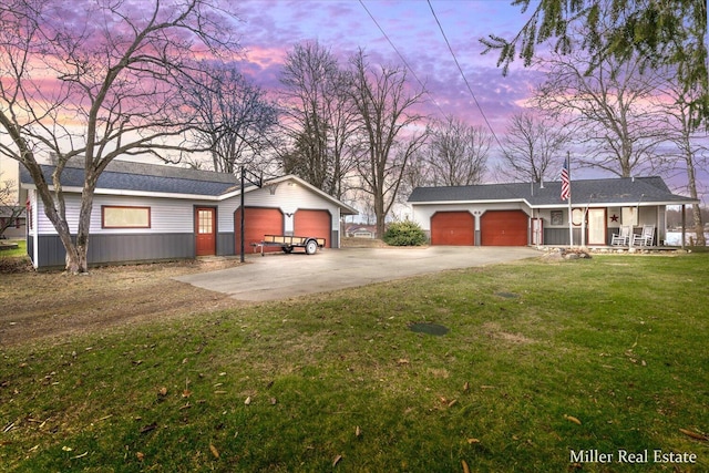 view of yard with driveway, covered porch, and an attached garage
