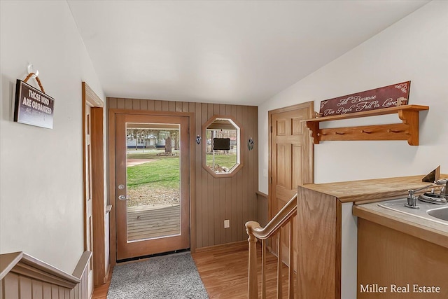 entryway featuring lofted ceiling, light wood-style flooring, and wood walls